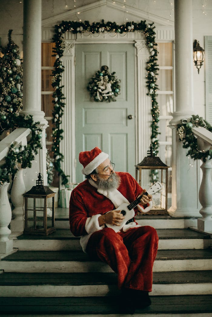 Santa Claus sitting on decorated porch steps, playing ukulele, surrounded by Christmas lights and greenery.
